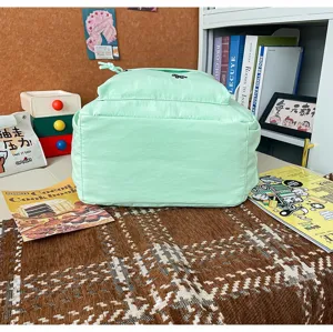 Detail view of mint green lightweight school backpack, casual lifestyle scene setup with books.