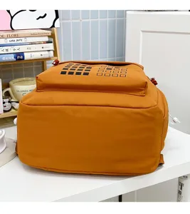 Detailed view of casual canvas student backpack in orange, featuring clean geometric grid design.