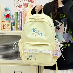 Close-up detail of the cute yellow canvas backpack featuring delicate snowflake embroidery and white lace trim.