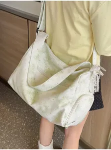 Detailansicht der weichen Stoff-Umhängetasche mit grünem Sternenprint und hübschem Spitzenanhänger.