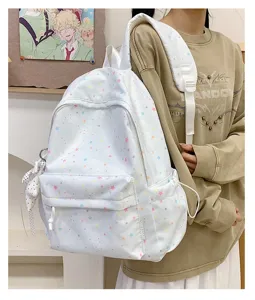 Close-up detail of white canvas backpack featuring colorful star prints and front pocket.