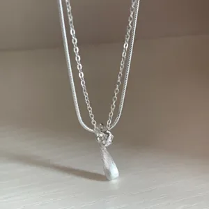 Detailed close-up shot of the double layer silver necklace with exquisite teardrop pendant.