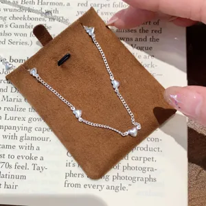Detailed close-up of a delicate silver-tone necklace with multiple cute heart charms on a book.