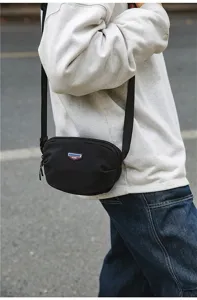Detail shot of black outdoor canvas crossbody shoulder bag with adjustable strap and zip.