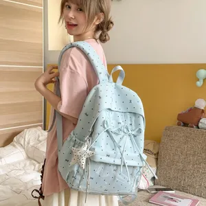 Light blue polka dot bow student backpack detail view showcasing cute design in bedroom.