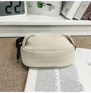 Detail view of a minimalist beige crossbody shoulder bag, featuring clean fabric and smooth lines.