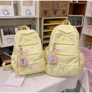 New 2026 yellow school backpack for teen girls, large capacity casual daypack with cute pendants.