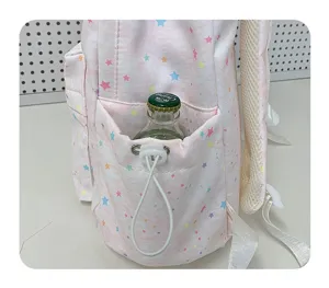 Detail view of pink star print backpack side pocket with drawstring and bottle storage.