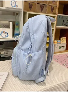 Light blue embossed student backpack side detail showing large capacity and straps.