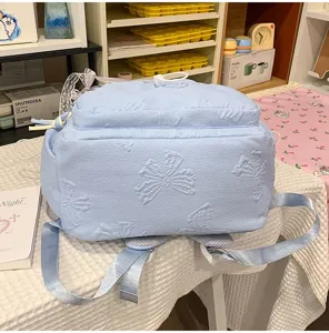 Light blue student schoolbag with cute embossed bow details, large capacity daily backpack.