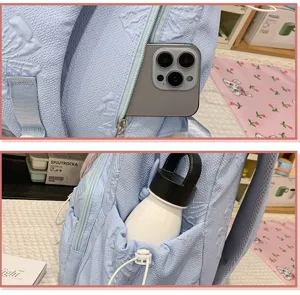 Detailed view of the light blue embossed school backpack, highlighting multi-pocket design.