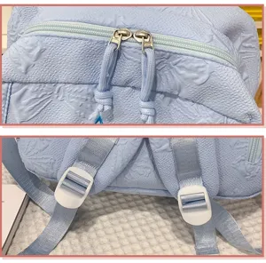 Light blue backpack detail shot featuring double zippers, pulls and adjustable straps.