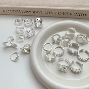 Primer plano de anillos abiertos plateados irregulares, detalles de joyería geométrica mate.