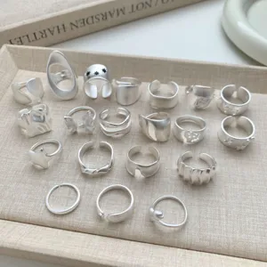 Vista detallada de varios anillos abiertos geométricos de plata mate, diseño minimalista.