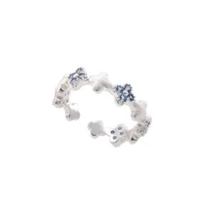 Close-up detail of a sweet floral clover open ring with blue stones and frosted finish.