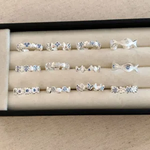 Detailed close-up view of various sparkling silver star and floral rings neatly displayed.