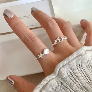 Detailaufnahme von Silberringen mit Seestern Muschel und hohlen Knoten Mustern am Finger.