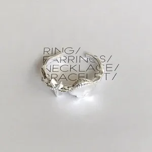 Nahaufnahme eines silbernen offenen Rings mit filigranem Seestern und Muschel-Design.