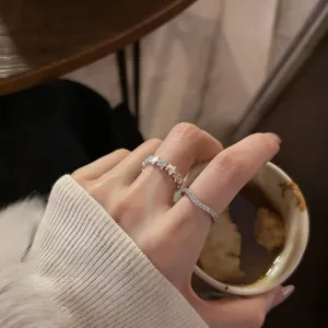 Detailed shot of stackable silver star and wave rings on fingers, elegant fashion jewelry.