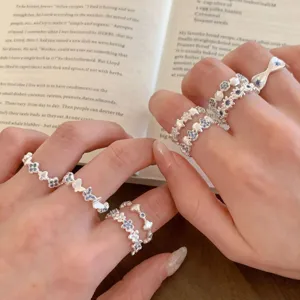 Close-up detail of multi-layered silver rings with blue crystal floral and star motifs.