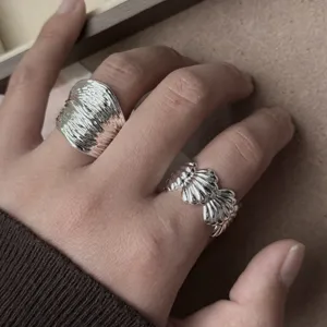 Primer plano de anillos de plata modernos con textura irregular y diseño de concha.