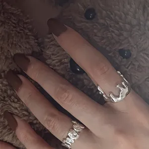 Detailaufnahme von unregelmäßigen flüssigen Metall-Offenen Ringen am Finger, Schmuck.