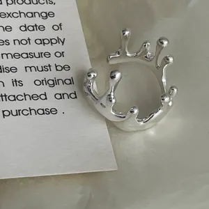 Detailaufnahme eines unregelmäßigen silbernen offenen Rings mit einem fließenden Spritzdesign.