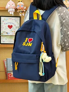 Detailed view of navy blue student backpack with embroidered front pocket and yellow straps.