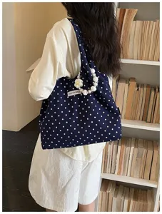 Detail view of navy blue polka dot canvas shoulder bag with chic pearl and flower strap.