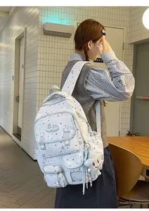 Detailed view of white star print canvas student backpack with multiple pockets and cute pendant.
