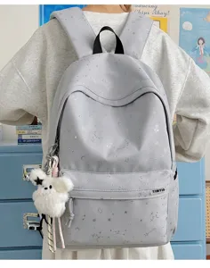 Detail shot of the grey star print college backpack with cute plush bear pendant and front pocket.