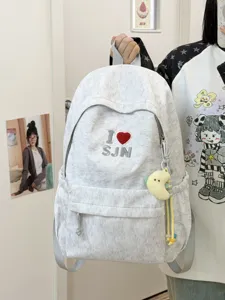 Detailed view of grey mottled casual school backpack featuring embroidery and plush charm.