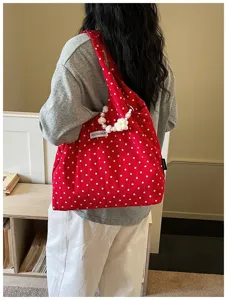 Red polka dot canvas shoulder bag detail view with pearl and floral handle decoration.