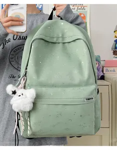 Close-up detail of the cute starry print backpack with plush pendant and handy front pocket.