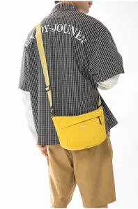 Vista detallada del bolso cruzado de nailon amarillo, bolso de pecho llevado por el modelo.