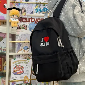 Black canvas student backpack close-up, featuring cute embroidered heart patch and zippers.