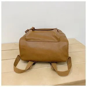 Vue détaillée de la poche du sac à dos en cuir PU marron, logo embossé et bretelles en toile.