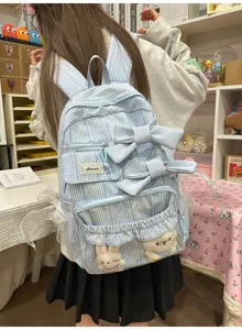 Close-up detail of the light blue plaid school backpack featuring dual bows and cute plush toys.
