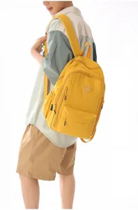 Detailed view of yellow nylon backpack worn by model, showing multi-pocket design.