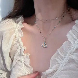 Double layer necklace detail showing colorful butterfly pendant and dainty bead chain design.