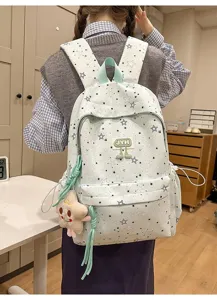 Detailed view of the mint green star patterned backpack with plush pendant and multiple compartments.