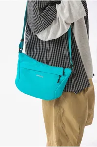 Vista detallada del bolso cruzado de nylon de moda en cian brillante, estilo urbano informal.