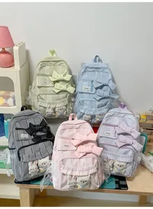 Close-up detail of various colored plaid backpacks with bows and cute plush animals.