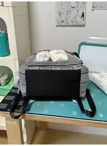 Detail view of the black and white grid backpack showcasing its transparent front pocket design.