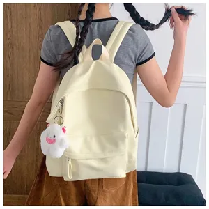 Vue détaillée d'un sac à dos décontracté jaune clair élégant porté avec un charm en peluche.