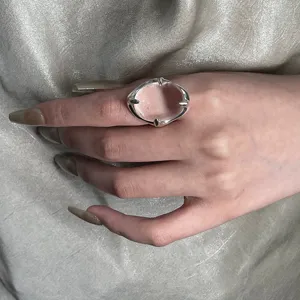 Primer plano detallado de un anillo de plata llamativo con gema rosa translúcida.