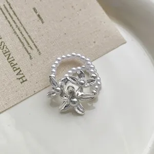 Detailansicht des eleganten doppellagigen Perlenrings mit silbernen Blumenanhängern.