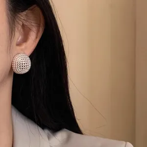 Detailed close-up of exquisite hollow mesh button stud earrings showing refined textured design.
