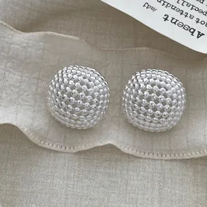 Close up of exquisite silver metal mesh dome earrings with intricate hollow spherical design detail