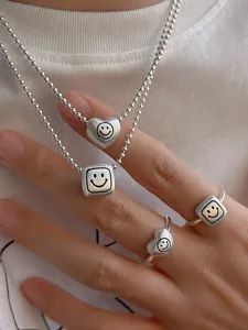 Detailed close-up view of brushed matte silver geometric heart and square smiley ring set.